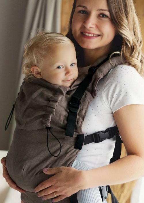 Little Frog Prime Pure Linen Frappe bruine draagzak voorop gedragen door een moeder met baby, schouder- en heupband zichtbaar