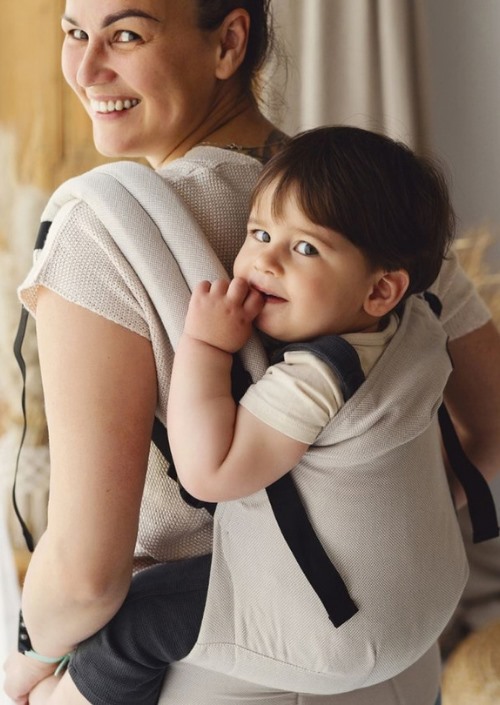 Peuter in beige Little Frog Swift draagzak op de rug van een vrouw
