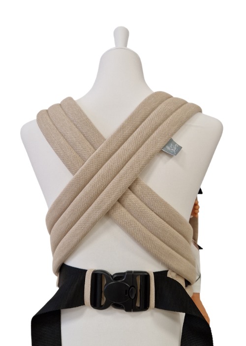 Beige Storchenwiege Talemo met gekruiste schouderbanden en zwarte heupband met gesp, getoond op de rugzijde van een paspop