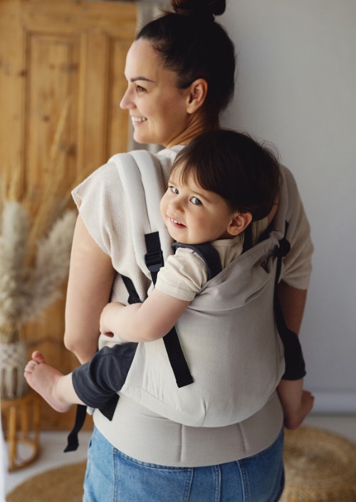 Beige Little Frog Swift Toddler Carrier met peuter op de rug gedragen door een vrouw