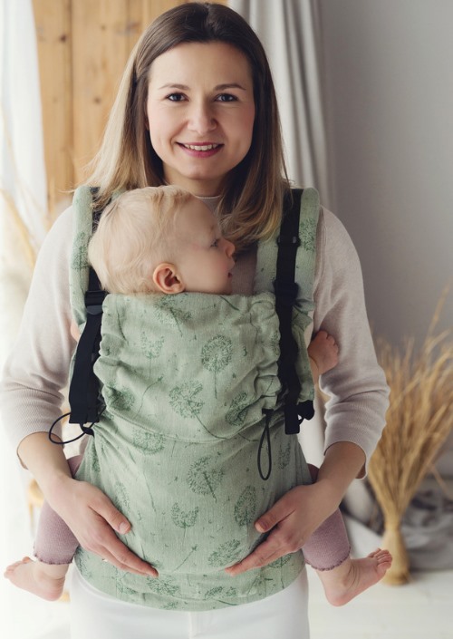 Little Frog Prime Linen Flow Lightness Green Dandelion groene draagzak met dandelion-patroon, vooraanzicht gedragen door een vrouw met baby