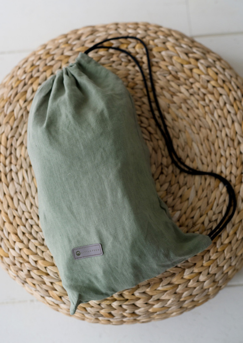 Groen opbergtasje van de Little Frog Preschooler Pure Linen Grove op een gevlochten ondergrond.