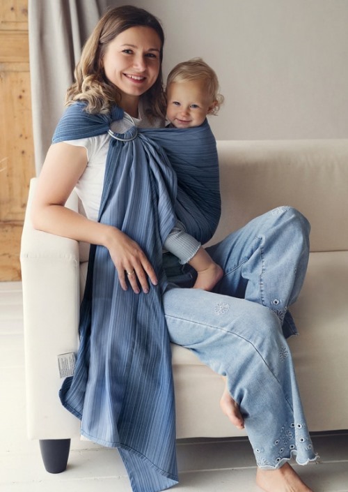 Moeder draagt kind in blauwgrijze Little Frog ringsling met ringen op de schouder