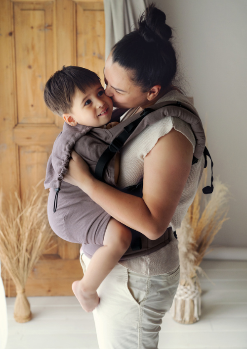 Ouder knuffelt een kindje in de Little Frog Preschooler Pure Linen full-buckle draagzak.