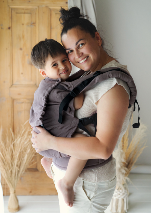 Lachende ouder met kindje in de Little Frog Preschooler Pure Linen draagzak in taupekleur.