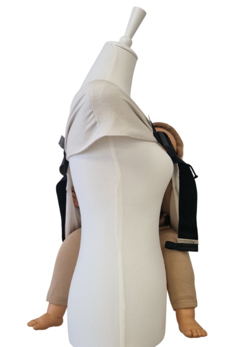 Storchenwiege Hipino Moonstone beige draagzak op mannequin, met zichtbaar babyhoofdje en beentjes aan de zijkanten