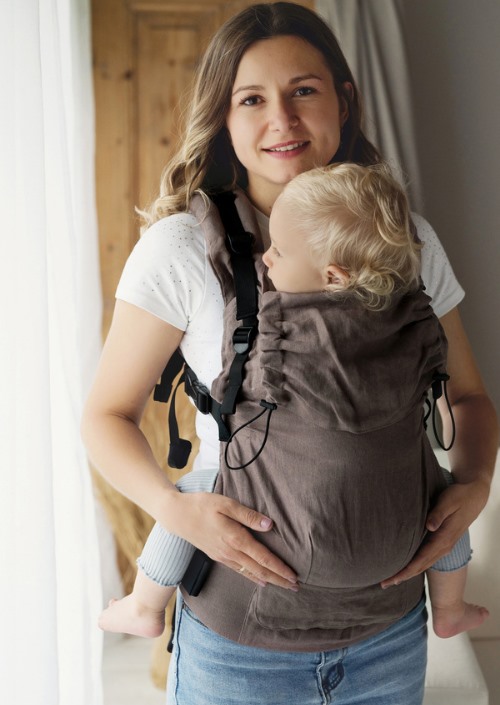 Little Frog Prime Pure Linen Frappe bruine draagzak in vooraanzicht, gedragen door een vrouw met kind op de borst