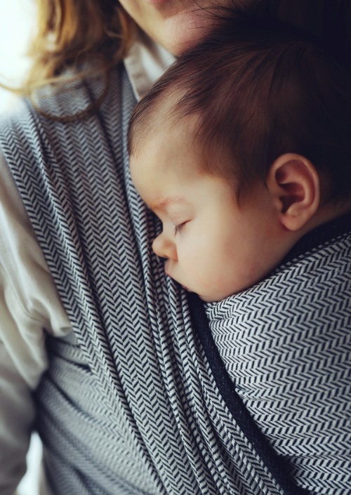 Slapende baby gedragen in zwart-wit draagdoek met visgraatpatroon
