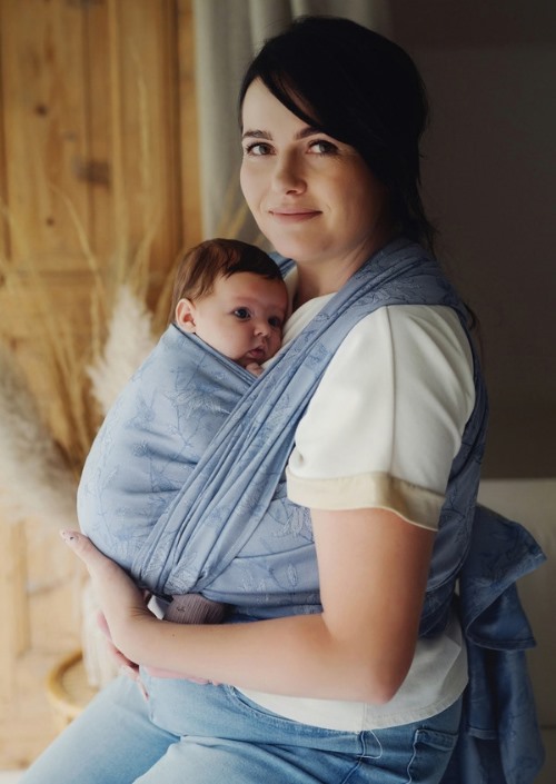 Moeder draagt baby in lichtblauwe Little Frog draagdoek met subtiel bladpatroon