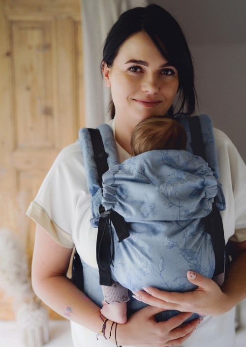 Moeder draagt baby in lichtblauwe Little Frog Prime Carrier met donkerblauwe botanische print, vooraanzicht