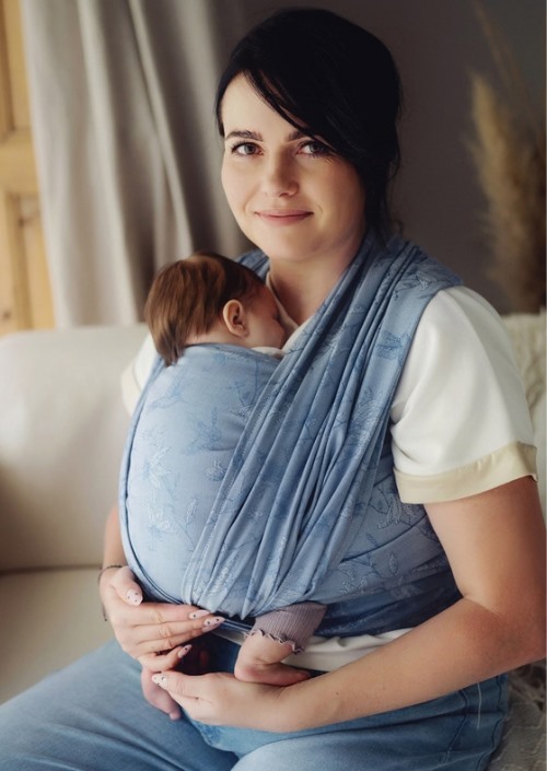 Vrouw draagt slapende baby in lichtblauwe Little Frog draagdoek met ingeweven patroon