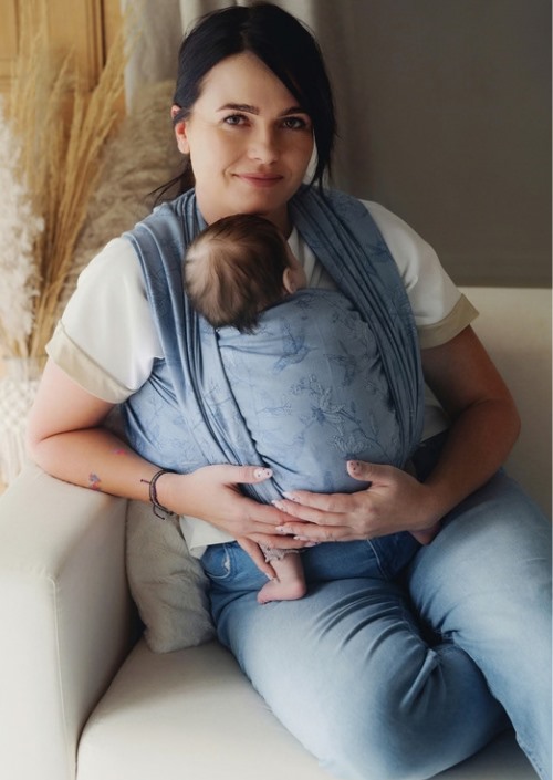 Moeder draagt baby voorop in blauwe Little Frog draagdoek met subtiel botanisch patroon