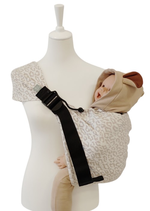 Storchenwiege Hipino Mara draagzak met beige luipaardprint en zwarte schouderband op paspop met baby